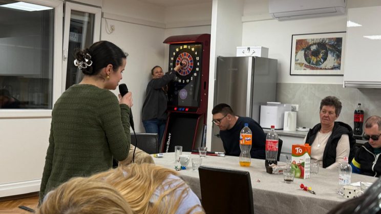 Anđela za mikrofonom, ekipa čeka red za pikado, ostali provode ugodno vrijeme u sali u razgovoru i druženju