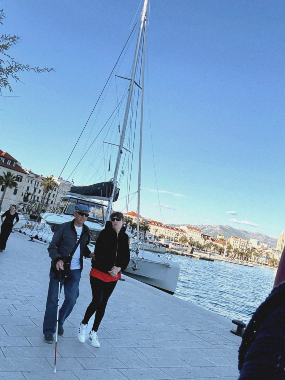 Drago i Dunja pod ruku setaju Zapadnom obalom u Splitu. U pozadini se nalazi dvostruki katamaran.