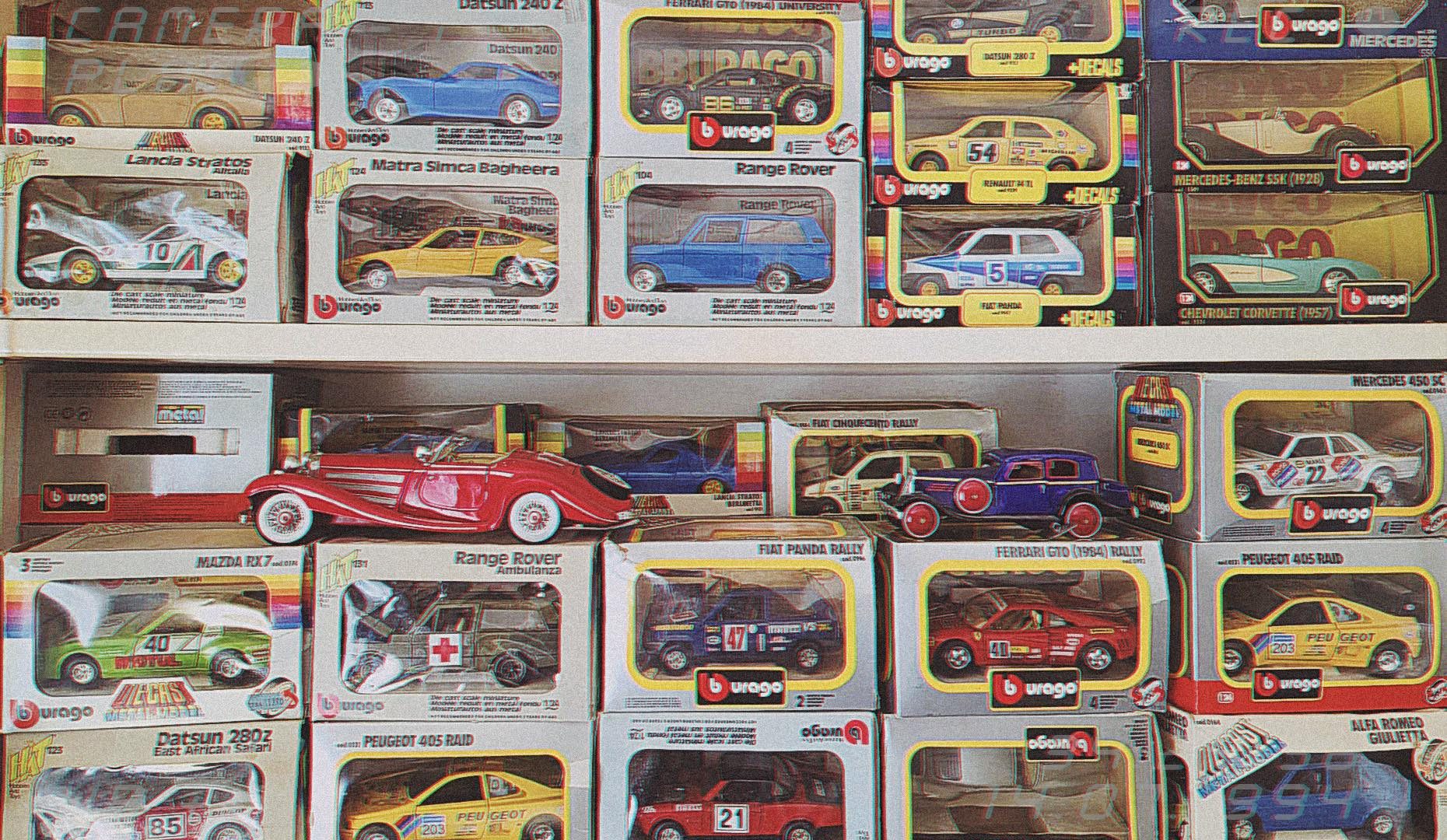 Na policama je izložena kolekcija zapakiranih Bburago metalnih modela automobila, različitih marki i boja, među kojima su klasični i trkaći automobili brendova poput Peugeota, Range Rovera i Ferrarija.